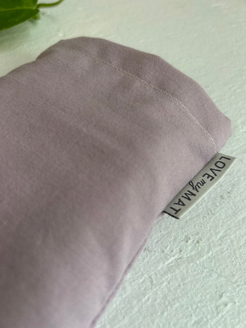 Purple fabric eye pillow with a label on a light green background