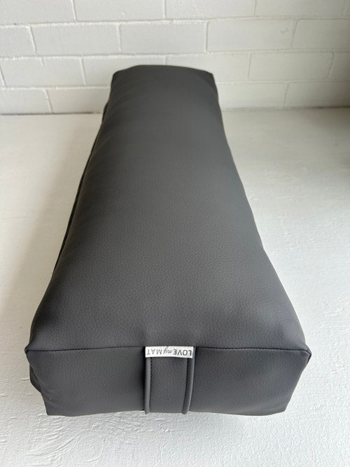 Gray yoga bolster with a brand label on a light gray background
