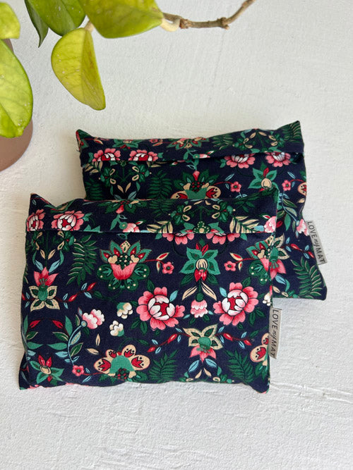 Two floral-patterned Hand Weights on a white surface with a plant in the corner.
