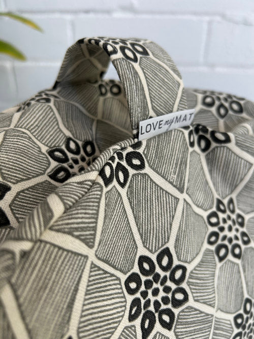 Patterned meditation cushion with a visible brand tag 'LOVE my MAT' against a white brick wall.