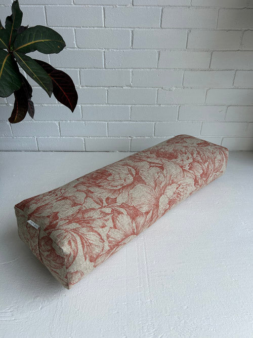 Floral Orange Yoga Bolster with floral pattern on a white surface and tiled wall background
