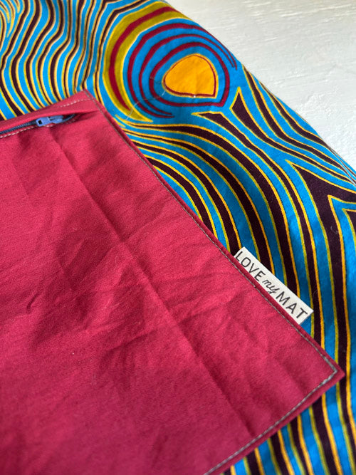 Close-up of a maroon fabric with a colorful patterned background