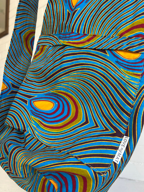 Colorful patterned fabric yoga mat bag with swirling peacock design on a plain background