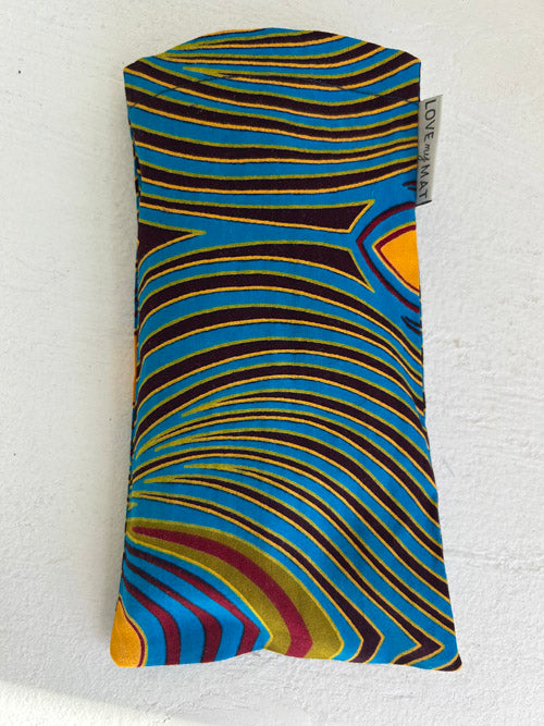 Colorful patterned eye pillow with a visible brand tag on a white background