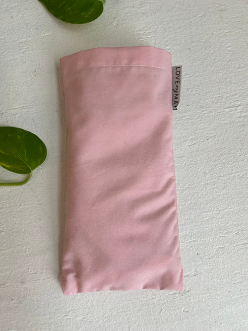 Folded pink fabric eye pillow with a tag on a white background