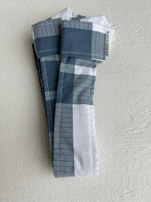 Plaid fabric mat strap on a textured light gray background