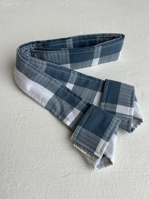 Blue and white plaid yoga mat strap on a light gray background