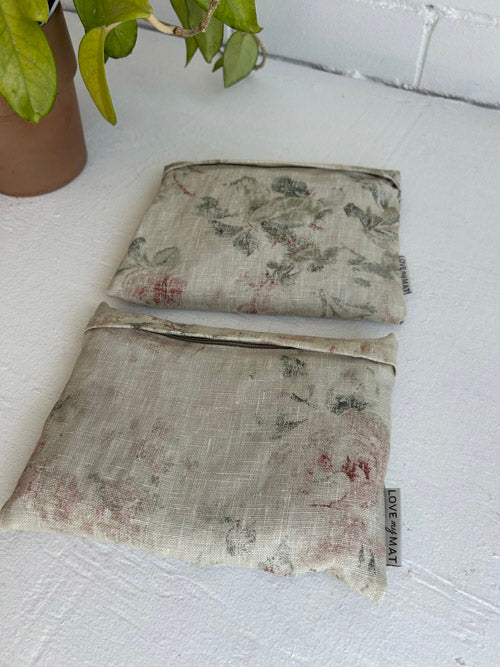 Two floral-patterned fabric handweights on a white surface with a plant in the background.