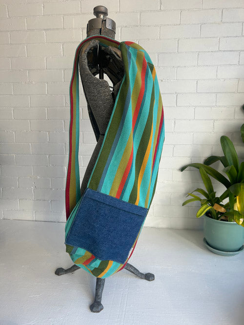 Colorful striped yoga bag on a stand with a white brick wall background