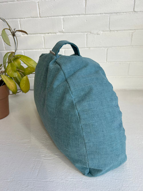 Teal Yoga or Meditation Cushion on a white surface with a white brick wall background
