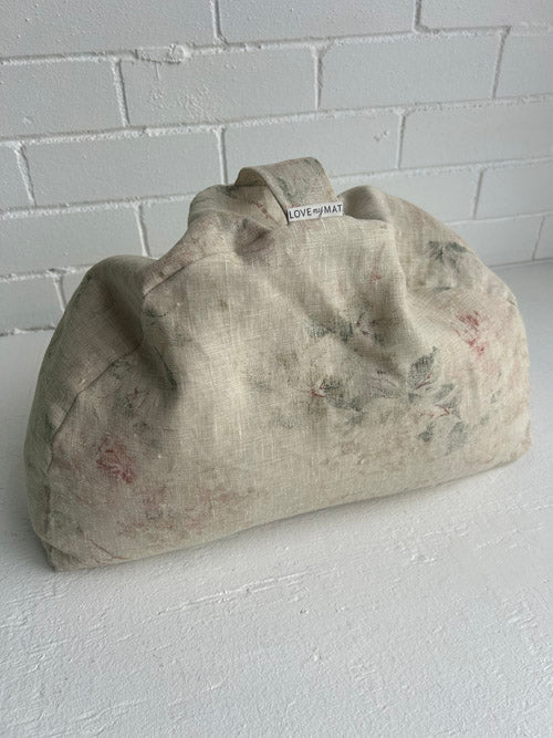 Textured beige clutch bag on a white surface with a light gray brick wall background