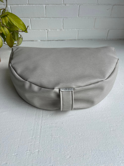 Warm grey sit meditation cushion with a brand label on a white surface