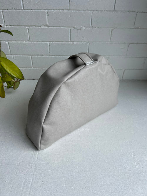 Gray sit pillow on a white surface with a light gray brick wall background