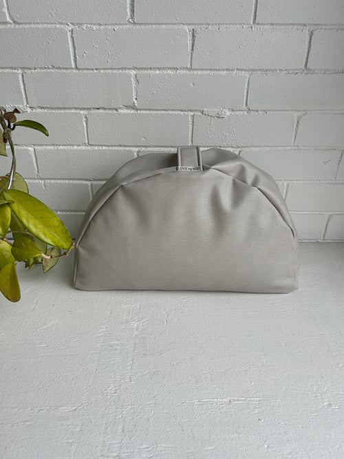 Brownish grey vinyl sit cushion on a light gray surface with a white brick wall background