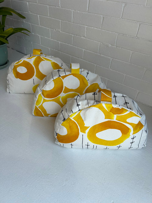 Three fabric-covered meditation cushions  with a yellow and white pattern on a white surface.