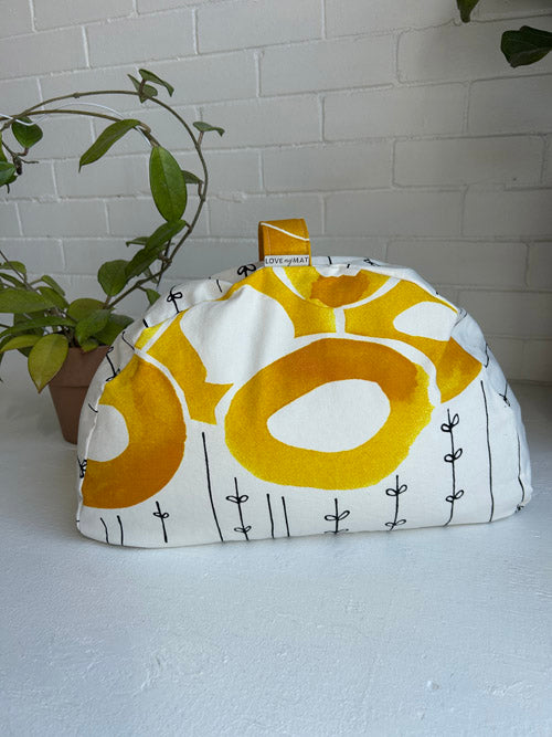 Fabric Sit Cushion with yellow and white pattern on a white surface with a plant in the background