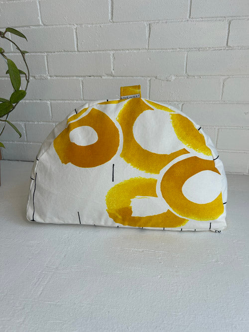 White with yellow floral pattern meditation cushion on a white surface and light gray brick wall background
