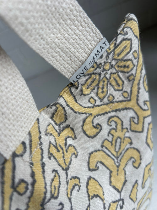  Yellow and gray patterned sandbag close up on a gray background, featuring a 'LOVE MY MAT' label.