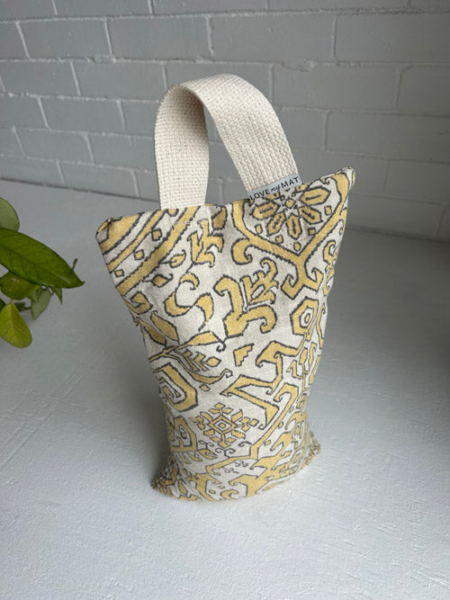 Fabric sandbag bag with yellow and white pattern on a light surface