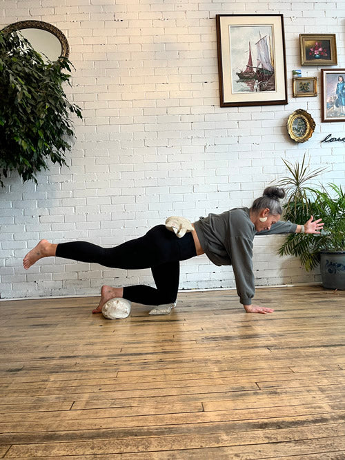Person practicing yoga in a room with white brick walls and framed pictures.