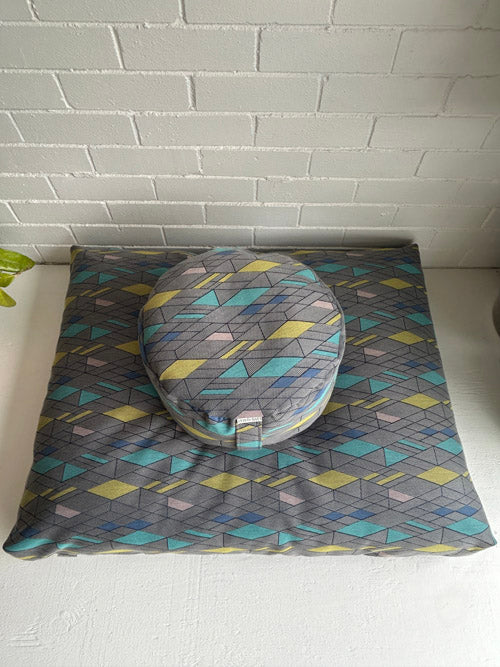 geometric pattern floor cushions against a white tiled wall.