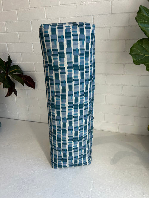 Tall rectangular fabric yoga bolster with blue and white pattern on a white floor.