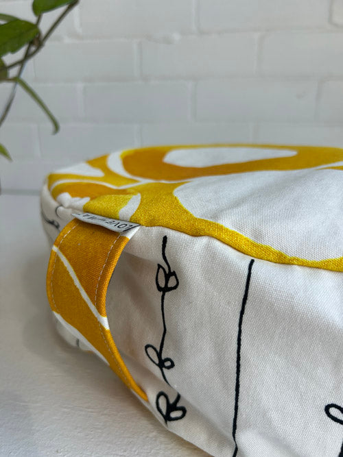 White pillow with yellow and black patterns on a white surface.